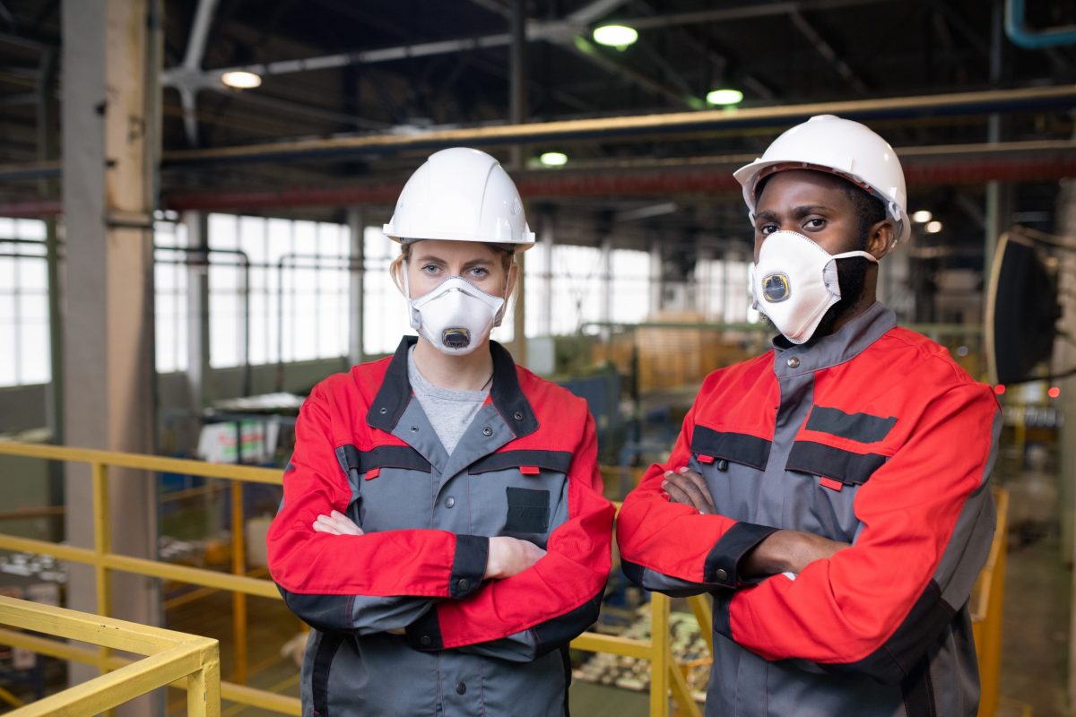 Man & Woman in overalls, hard hats & respirators in a factory : Asbestos, Health & Safety audits & advice from JCM Health & Safety, Liverpool.