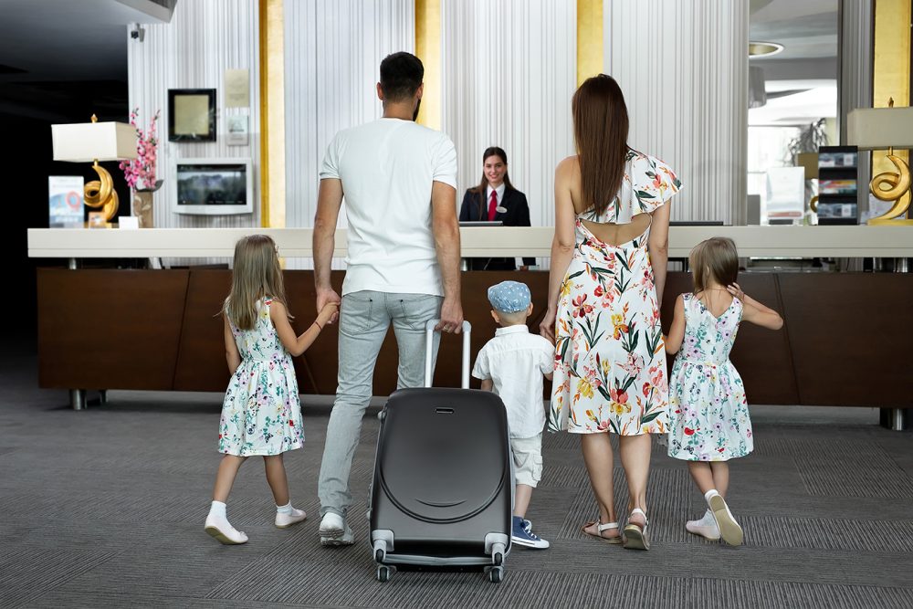 Family of five at hotel check-in, viewed from behind : Health & Safety Consultancy from JCM Health & Safety, Liverpool.